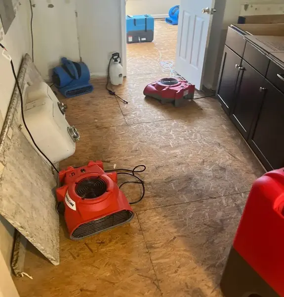 Air movers and a dehumidifier drying a kitchen subfloor